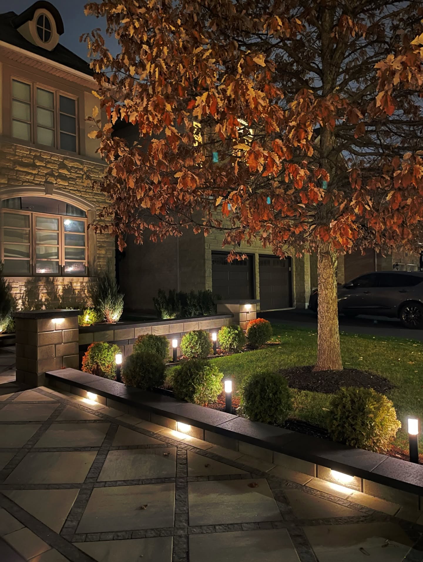 Front yard landscape lighting and raised stone planters at night in Mississauga